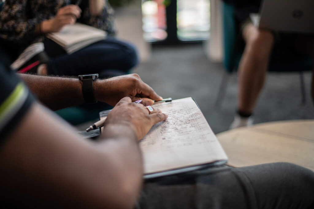 Office workplace individuals hands working, with hands on a notepad, pen in hand.